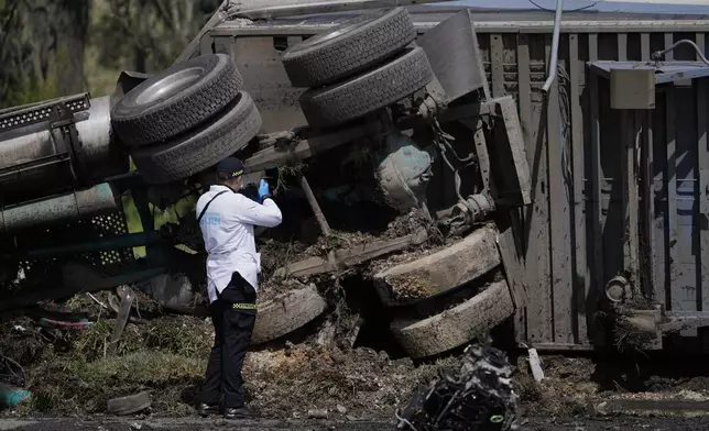 A forensics worker inspects the scene of a fatal, multiple vehicle accident in Cogua, Colombia, Wednesday, April 1, 2026. (AP Photo/Ivan Valencia)