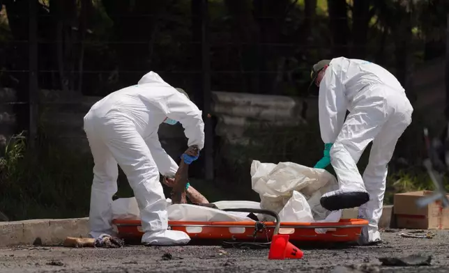 Forensics remove a body from a multiple vehicle accident in Cogua, Colombia, Wednesday, April 1, 2026. (AP Photo/Ivan Valencia)