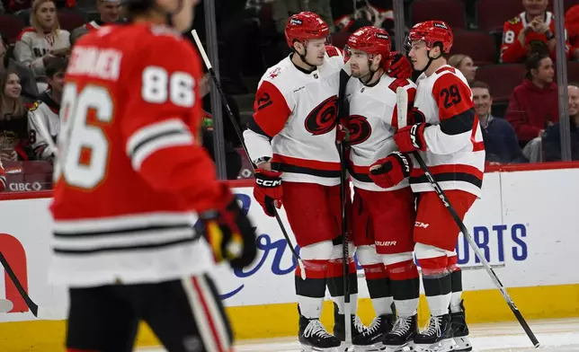 Carolina Hurricanes' Sean Walker (26) celebrates with teammates Alexander Nikishin (21) and Bradly Nadeau (29) after scoring a goal during the first period of an NHL hockey game against the Chicago Blackhawks in Chicago, Thursday, April 9, 2026. (AP Photo/Paul Beaty)
