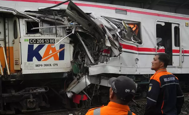 Workers examine the wreckages of trains after a collision in Bekasi, Indonesia, Tuesday, April 28, 2026. (AP Photo/Tatan Syuflana)