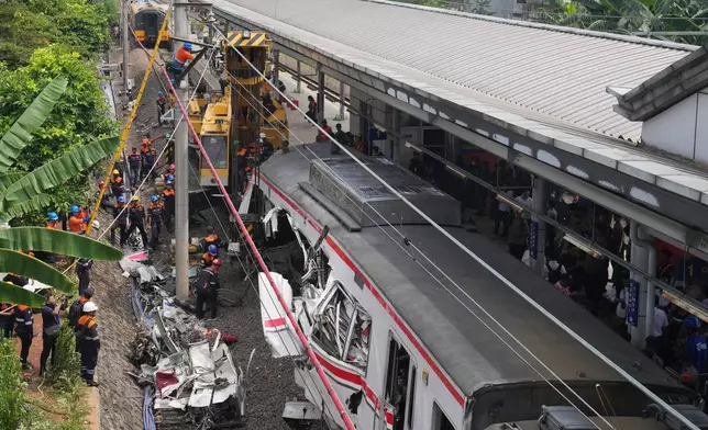 Workers use a heavy machine to remove the wreckage of a train after a collision in Bekasi, Indonesia, Tuesday, April 28, 2026. (AP Photo/Tatan Syuflana)