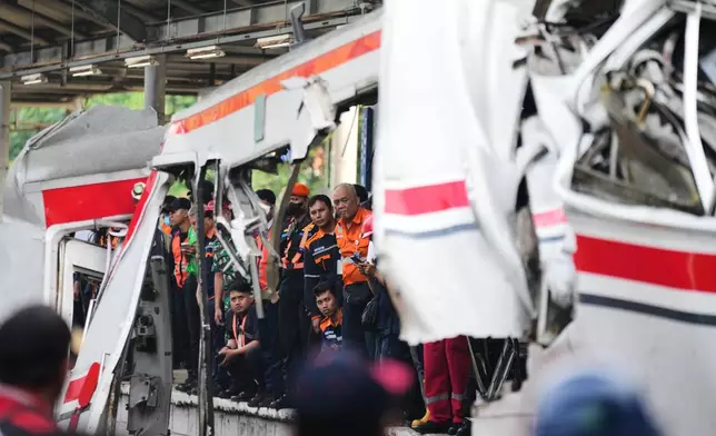 Workers and rescuers examine the wreckage following a train collision in Bekasi, Indonesia, Tuesday, April 28, 2026. (AP Photo/Tatan Syuflana)