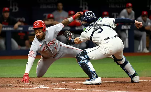 Cincinnati Reds' Dane Myers (17) avoids the tag from Tampa Bay Rays catcher Hunter Feduccia (9) as he scores during the sixth inning of a baseball game Tuesday, April 21, 2026, in St. Petersburg, Fla. (AP Photo/Jason Behnken)