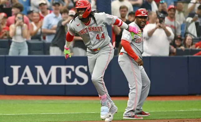 Cincinnati Reds' Elly de la Cruz (44) and third base coach Willie Harris celebrate de la Cruz's two run home run during the first inning of a baseball game against the Tampa Bay Rays Tuesday, April 21, 2026, in St. Petersburg, Fla. (AP Photo/Jason Behnken)