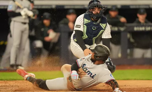 New York Yankees catcher Austin Wells, top, tags out Miami Marlins' Otto Lopez as he tries to score during the sixth inning of a baseball game, Sunday, April 5, 2026, in New York. (AP Photo/Seth Wenig)