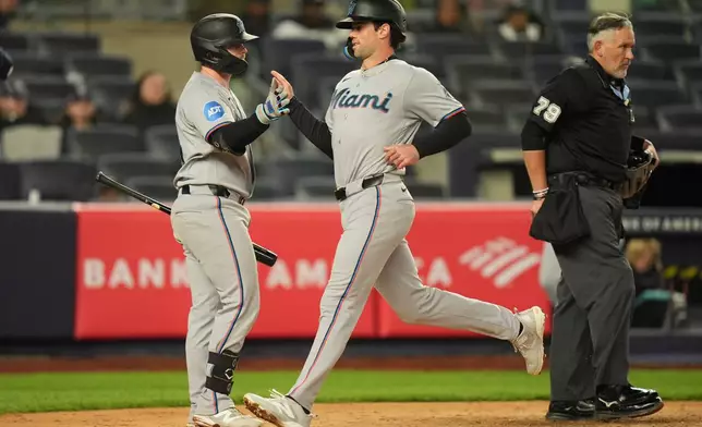 Miami Marlins' Liam Hicks, left, greets Graham Pauley, center, as he scores on a single hit by Xavier Edwards during the eighth inning of a baseball game against the New York Yankees, Sunday, April 5, 2026, in New York. (AP Photo/Seth Wenig)