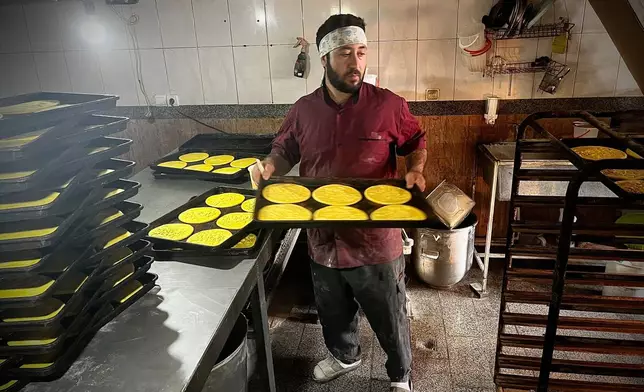 A baker pulls a rack of freshly baked local bread in a roadside bakery on Road 16 in Bostanabad, Iran, Thursday, April 9, 2026. (AP Photo/Francisco Seco)