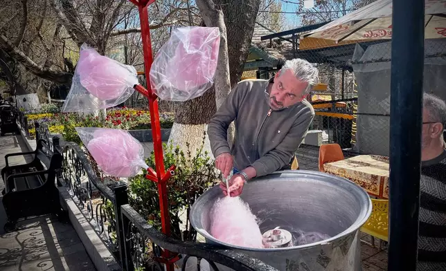 A man spins cotton candy for passersby in a public park near Road 2 in Tabriz, Iran, Thursday, April 9, 2026. (AP Photo/Francisco Seco)