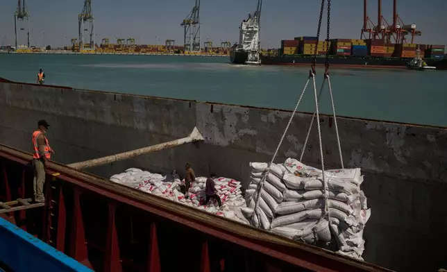 Workers offload cargo of rice from a feeder vessel into trucks at Umm Qasr Port, a deep-water port, in the city of Umm Qasr, Iraq, Friday, March 27, 2026. (AP Photo/Leo Correa)