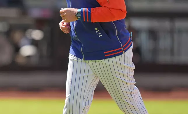 New York Mets manager Carlos Mendoza returns to the dugout after a pitching change during the sixth inning of the first baseball game of a doubleheader against the Colorado Rockies, Sunday, April 26, 2026, in New York. (AP Photo/Seth Wenig)