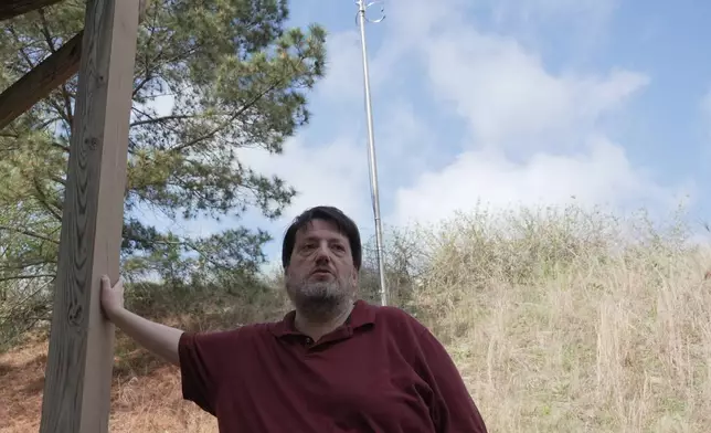 D.P. McIntire leans against a deck beneath the WKRP radio antenna in the backyard of his home in Raleigh, N.C., on Thursday, April 2, 2026. (AP Photo/Allen G. Breed)