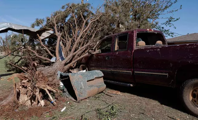 A vehicle at a home on Southgate Road sits under debris Friday, April 24, 2026, in a neighborhood that was damaged by a tornado Thursday in Enid, Okla. (AP Photo/Alonzo Adams)