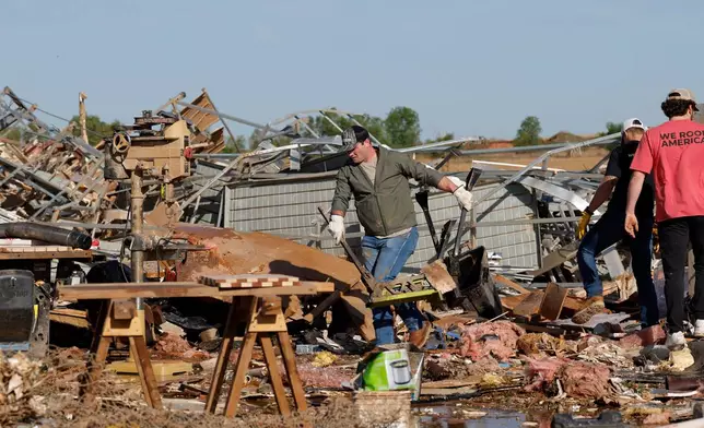 A man clears debris at a commercial woodworking shop in Enid, Okla., Friday, April 24, 2026, in the aftermath of a tornado that barreled through Oklahoma Thursday. (AP Photo/Alonzo Adams)