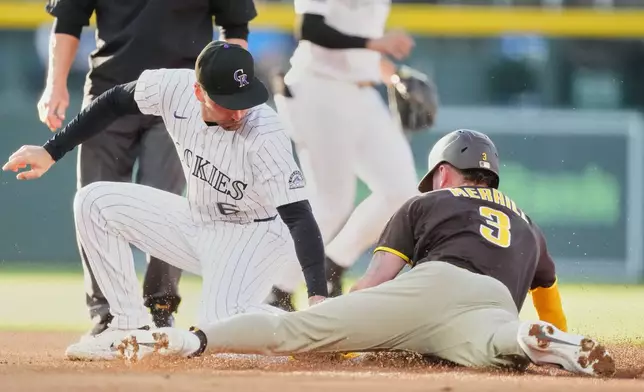 Colorado Rockies second baseman Edouard Julien, left, applies a late tag to San Diego Padres' Jackson Merrill as he steals second basein the first inning of a baseball game Wednesday, April 22, 2026, in Denver. (AP Photo/David Zalubowski)