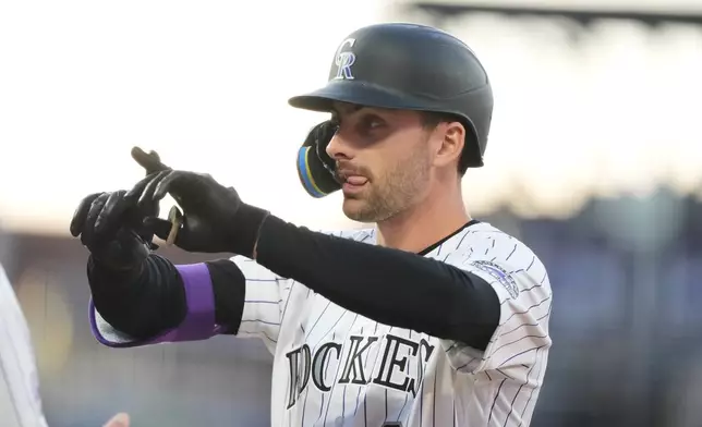 Colorado Rockies' Edouard Julien gestures to the dugout after reaching first base on an RBI single off San Diego Padres starting pitcher Walker Buehler in the second inning of a baseball game Wednesday, April 22, 2026, in Denver. (AP Photo/David Zalubowski)