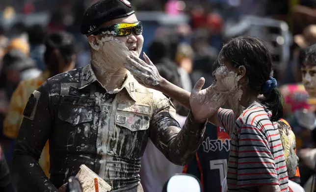 A participant puts powder on the face of a Thai police during the Songkran water festival to celebrate the Thai New Year in Prachinburi province, Thailand, Monday, April 13, 2026. (AP Photo/Wason Wanichakorn)