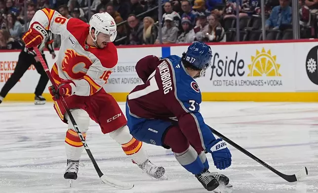 Calgary Flames center Morgan Frost, left, loses control of the puck to Colorado Avalanche defenseman Nick Blankenburg in the second period of an NHL hockey game Thursday, April 9, 2026, in Denver. (AP Photo/David Zalubowski)