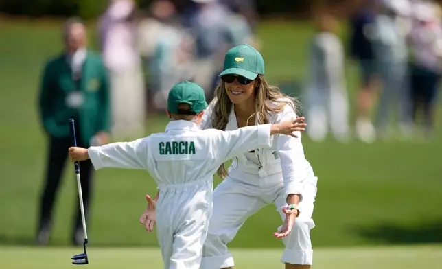 Sergio Garcia's wife Angela Akins, right, hugs their son, Enzo, on the third hole during par-3 contest ahead of the Masters golf tournament at the Augusta National Golf Club, Wednesday, April 8, 2026, in Augusta, Ga. (AP Photo/Ashley Landis)