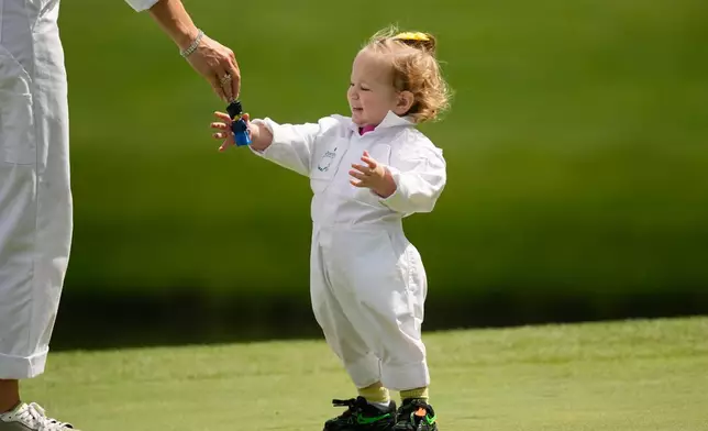 Jon Rahm's daughter, Alaia, reaches for a toy during par-3 contest ahead of the Masters golf tournament at the Augusta National Golf Club, Wednesday, April 8, 2026, in Augusta, Ga. (AP Photo/Gerald Herbert)