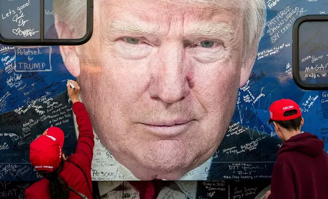 FILE - Supporters of Republican presidential nominee former President Donald Trump sign a bus before a campaign rally at the Butler Farm Show, Oct. 5, 2024, in Butler, Pa. (AP Photo/Julia Demaree Nikhinson, File)