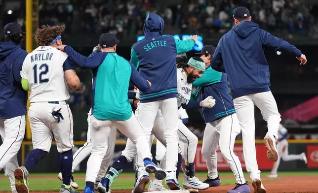 Seattle Mariners' J.P. Crawford, center facing, celebrates with teammates after hitting a game-winning RBI single against the Houston Astros during the ninth inning of a baseball game, Saturday, April 11, 2026, in Seattle. (AP Photo/Lindsey Wasson)