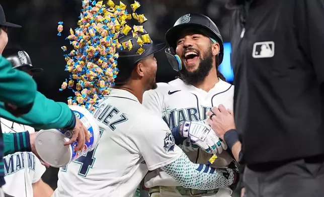 Seattle Mariners' J.P. Crawford, center, celebrates with Julio Rodríguez, left, after hitting a game-winning single to score Cole Young against the Houston Astros during the ninth inning of a baseball game, Saturday, April 11, 2026, in Seattle. (AP Photo/Lindsey Wasson)