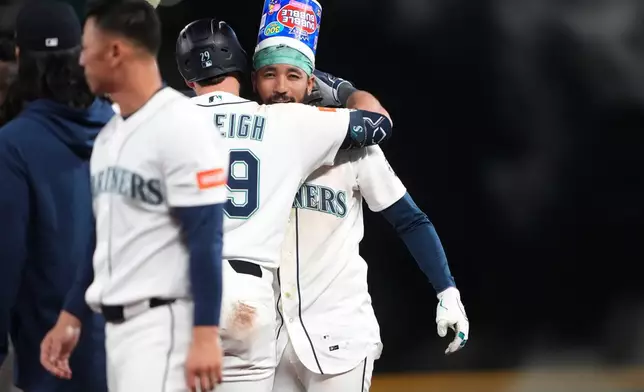 Seattle Mariners' J.P. Crawford, facing, celebrates with Cal Raleigh (29) after hitting a game-winning RBI single against the Houston Astros during the ninth inning of a baseball game, Saturday, April 11, 2026, in Seattle. (AP Photo/Lindsey Wasson)