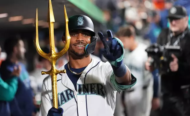 Seattle Mariners' Julio Rodríguez celebrates with the trident in the dugout after hitting a two-run home run against the Houston Astros during the fifth inning of a baseball game, Saturday, April 11, 2026, in Seattle. (AP Photo/Lindsey Wasson)
