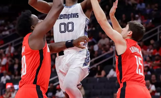 Memphis Grizzlies forward Dariq Whitehead (00) lays up a shot between Houston Rockets center Clint Capela, left, and guard Reed Sheppard (15) during the first half of an NBA basketball game Sunday, April 12, 2026, in Houston. (AP Photo/Michael Wyke)