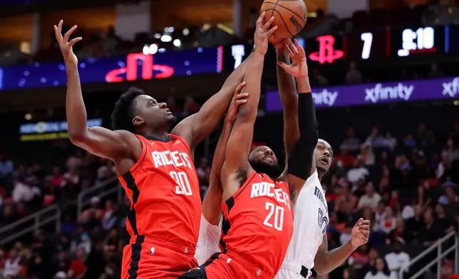 Houston Rockets center Clint Capela (30) and guard Josh Okogie (20) battle for a rebound with Memphis Grizzlies forward Dariq Whitehead, right, during the first half of an NBA basketball game Sunday, April 12, 2026, in Houston. (AP Photo/Michael Wyke)
