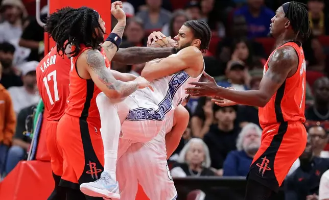 Memphis Grizzlies guard Rayan Rupert, center with ball, battles to keep a rebound between Houston Rockets forward Tari Eason, guard JD Davison, left, and forward Dorian Finney-Smith, right, during the first half of an NBA basketball game Sunday, April 12, 2026, in Houston. (AP Photo/Michael Wyke)