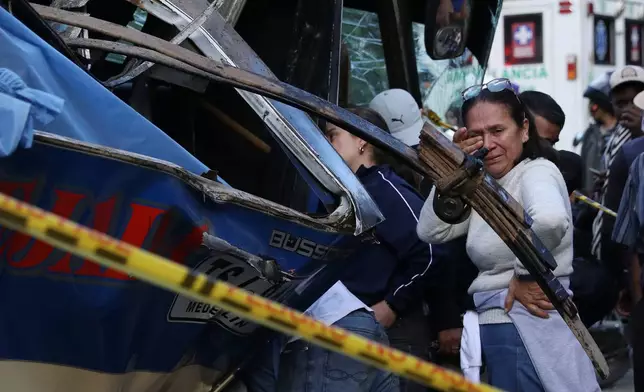 People gather around a bus hit by an explosive device on the Pan-American Highway in Cajibio, Colombia, Saturday, April 25, 2026, after an attack blamed by authorities on dissident groups of the former FARC rebels killed at least a dozen people. (AP Photo/Santiago Saldarriaga)