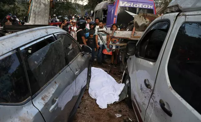 The covered body of a victim lies among vehicles damaged in an attack on the Pan-American Highway in Cajibio, Colombia, Saturday, April 25, 2026, where authorities said at least a dozen people were killed and blamed dissident groups of the former FARC rebels. (AP Photo/Santiago Saldarriaga)