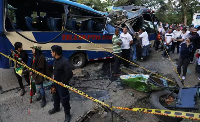 People gather around a bus hit by an explosive device on the Pan-American Highway in Cajibio, Colombia, Saturday, April 25, 2026, after an attack blamed by authorities on dissident groups of the former FARC rebels killed at least a dozen people. (AP Photo/Santiago Saldarriaga)