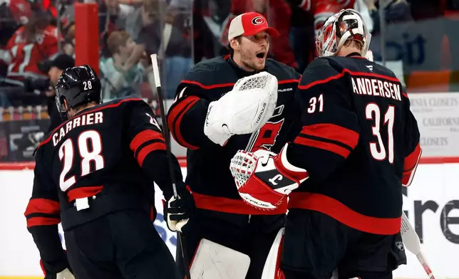 Carolina Hurricanes goaltender Brandon Bussi (32) congratulates goaltender Frederik Andersen (31) with William Carrier (28), following the second overtime of Game 2 of an NHL hockey Stanley Cup first-round playoff series against the Ottawa Senators in Raleigh, N.C., Monday, April 20, 2026. (AP Photo/Karl DeBlaker)