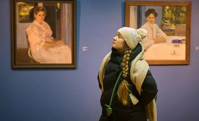 A visitor at Ukraine's National Art Museum is bundled up due to power outages caused by Russian air attacks on the country's energy system, affecting the museum's temperature during winter in Kyiv, Ukraine, on Feb. 6, 2026. (AP Photo/Efrem Lukatsky)