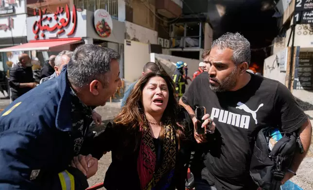 A woman is assisted at the site of an Israeli airstrike that struck an apartment building in Beirut, Lebanon, Wednesday, April 8, 2026. (AP Photo/Bilal Hussein)