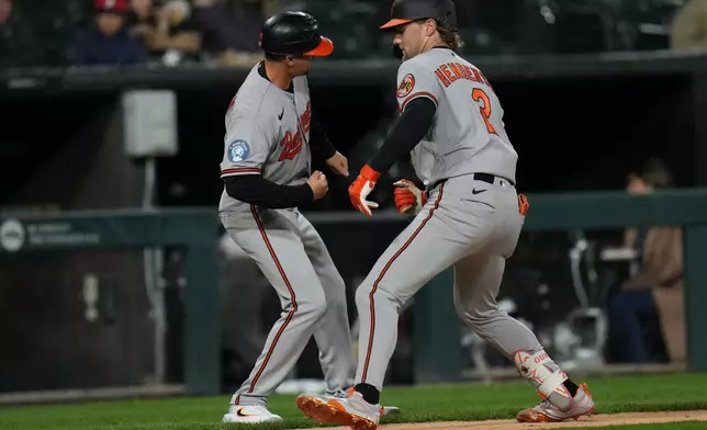 Baltimore Orioles' Gunnar Henderson (2), right, celebrates with third base coach Buck Britton, left, after hitting a home run during the sixth inning of a baseball game against the Chicago White Sox, Monday, April 6, 2026, in Chicago. (AP Photo/Erin Hooley)