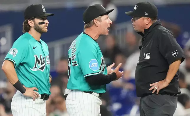 Miami Marlins manager Clayton McCullough, center, argues a call with first base umpire Cory Blaser, right, as first baseman Connor Norby, left, looks on during the first inning of a baseball game against the Milwaukee Brewers, Sunday, April 19, 2026, in Miami. (AP Photo/Lynne Sladky)