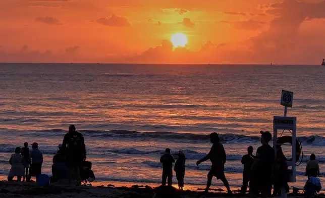 Spectators watch the sunrise from the beach at Cherie Down Park in Cape Canaveral, Fla., as they wait to watch the launch of the Blue Origin New Glenn rocket from the Cape Canaveral Space Force station, Sunday, April 19, 2026, in Cape Canaveral, Fla. (AP Photo/John Raoux)