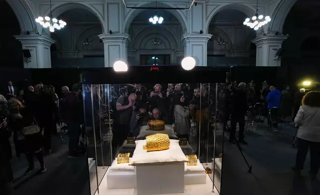 Journalists take photos of the Dacian gold items, a 2,500-year-old helmet and wristbands, stolen from a museum in the Netherlands and then recovered by Dutch authorities, after they were presented upon being returned at the National Museum of Romanian History, in Bucharest, Romania, Tuesday, April 21, 2026. (AP Photo/Andreea Alexandru)