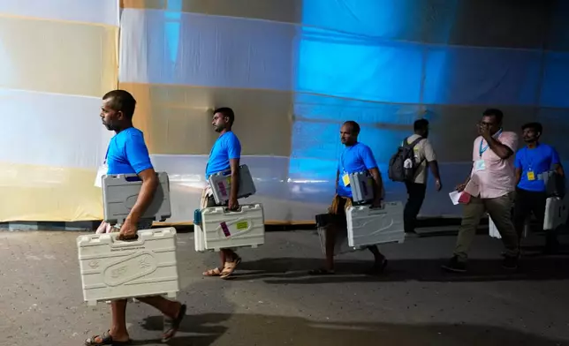 Workers carry Electronic Voting Machines from strong room to a counter at a distribution centre ahead of the second phase of elections in West Bengal state, in Kolkata, India, Tuesday, April 28, 2026. (AP Photo/Bikas Das)