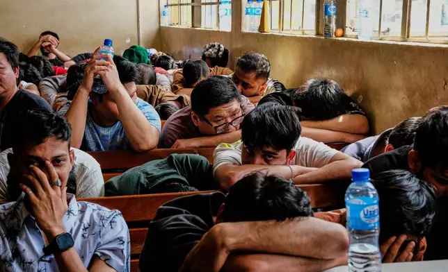 Detainees sit in a room after Ugandan authorities arrested dozens of foreigners in a crackdown on illegal migration in Kampala, Uganda, Tuesday, April 28, 2026. (AP Photo/Hajarah Nalwadda)