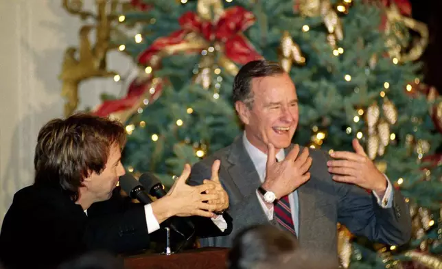 FILE - Comic Dana Carvey, left, shows President George H.W. Bush how to imitate himself, Dec. 8, 1992, at the White House in Washington. (AP Photo/Dennis Cook, File)