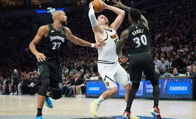 Denver Nuggets center Nikola Jokic (15) works toward the basket as Minnesota Timberwolves center Rudy Gobert (27) and forward Julius Randle (30) defend during the first half in Game 3 of a first-round NBA basketball playoff series, Thursday, April 23, 2026, in Minneapolis. (AP Photo/Abbie Parr)