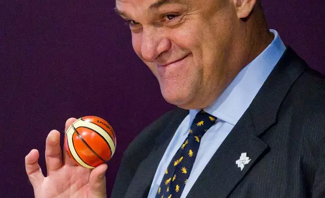 FILE - Brazil's former basketball player Oscar Schmidt shows a miniature basketball containing the name of a country during the draw for the London 2012 Olympic men's basketball tournament in Rio de Janeiro, April 30, 2012. Schmidt, whom his Brazil compatriots know as the “Holy Hand,” died. Friday, April 17, 2026. He was 68. (AP Photo/Victor R. Caivano, File)