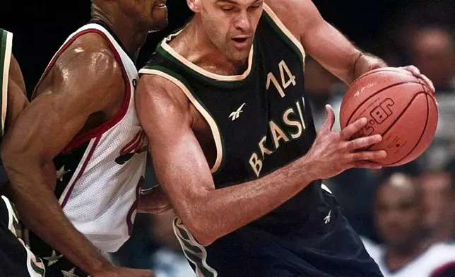 FILE - Brazil's Oscar Schmidt (14) drives past Scottie Pipen (8) of the United States during the quarterfinals of basketball competition at the Centennial Summer Olympic Games in Atlanta, July 30, 1996. Schmidt, whom his Brazil compatriots know as the “Holy Hand,” died. Friday, April 17, 2026. He was 68. (AP Photo/Hans Deryk, File)