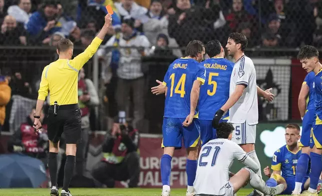 Referee Clement Turpin shows a red card to Italy's Alessandro Bastoni (21) during the World Cup qualifying playoff final soccer match between Bosnia and Italy in Zenica, Bosnia, Tuesday, March 31, 2026. . (Fabio Ferrari/LaPresse via AP)