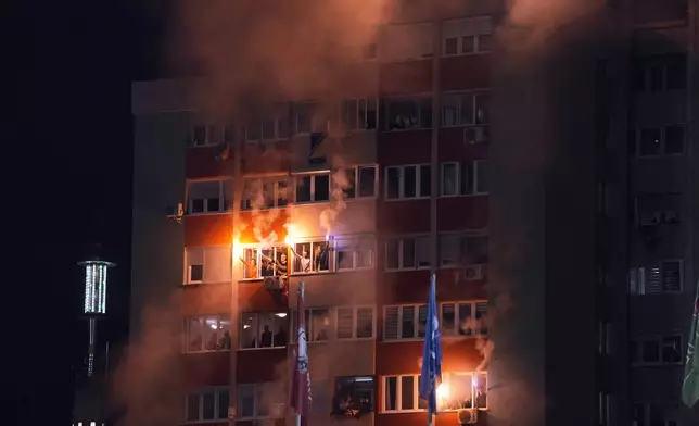 Bosnia supporters light flares as they watch from an apartment building just outside the stadium during the World Cup qualifying playoff final soccer match between Bosnia and Italy in Zenica, Bosnia, Tuesday, March 31, 2026. (Fabio Ferrari/LaPresse via AP)