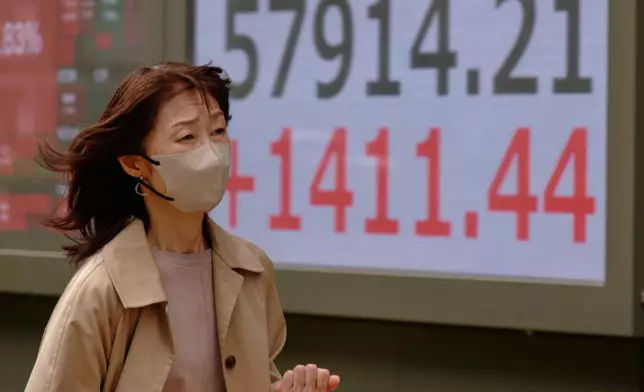 A person walks in front of an electronic stock board showing Japan's Nikkei index at a securities firm Tuesday, April 14, 2026, in Tokyo. (AP Photo/Eugene Hoshiko)